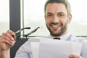 Produktmanager nimmt sich die Brille von der Nase und lächelt in die Kamera