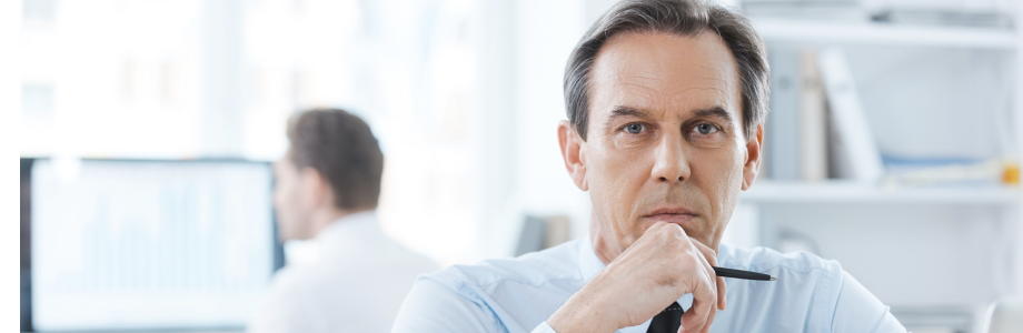 Mann am Schreibtisch schaut ernsthaft zum Betrachter