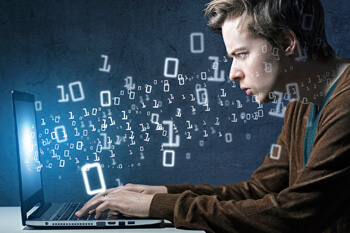 Software-Entwickler programmiert etwas am Laptop, dabei fliegen ihm digitale Zahlen aus dem Bildschirm entgegen