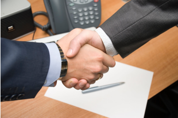 Zwei Männer im Anzug geben sich zum Vertragsabschluss die Hände