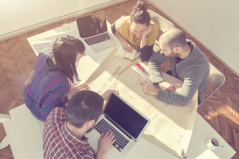 Vier Studentinnen und Studenten sitzen um einen Tisch und diskutieren