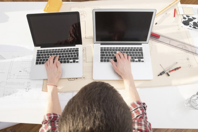 Student sitzt an zwei Laptops gleichzeitig